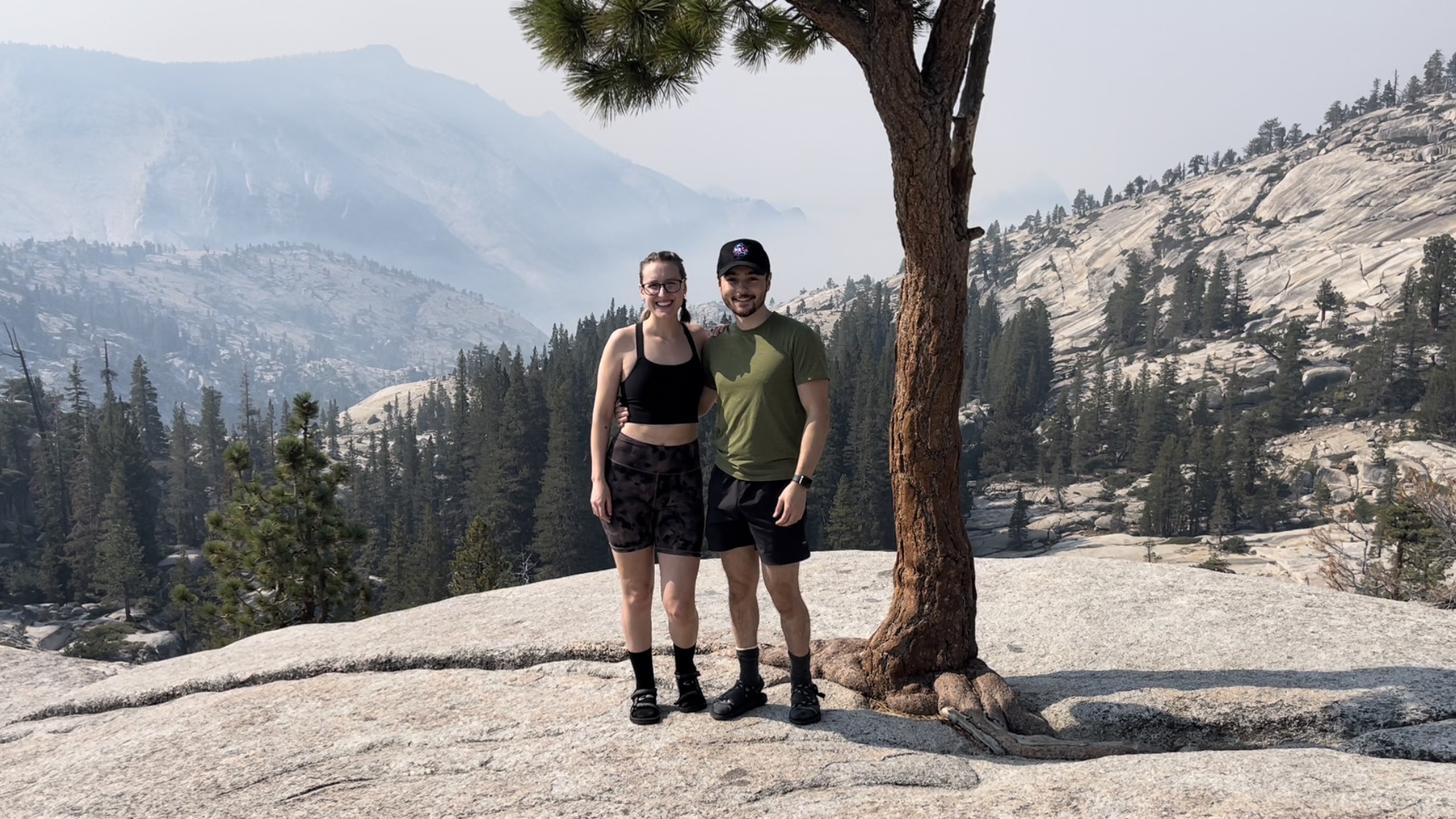 The website owner and her significant other standing in front of a valley in Yosemite National Park with a tree in the foreground