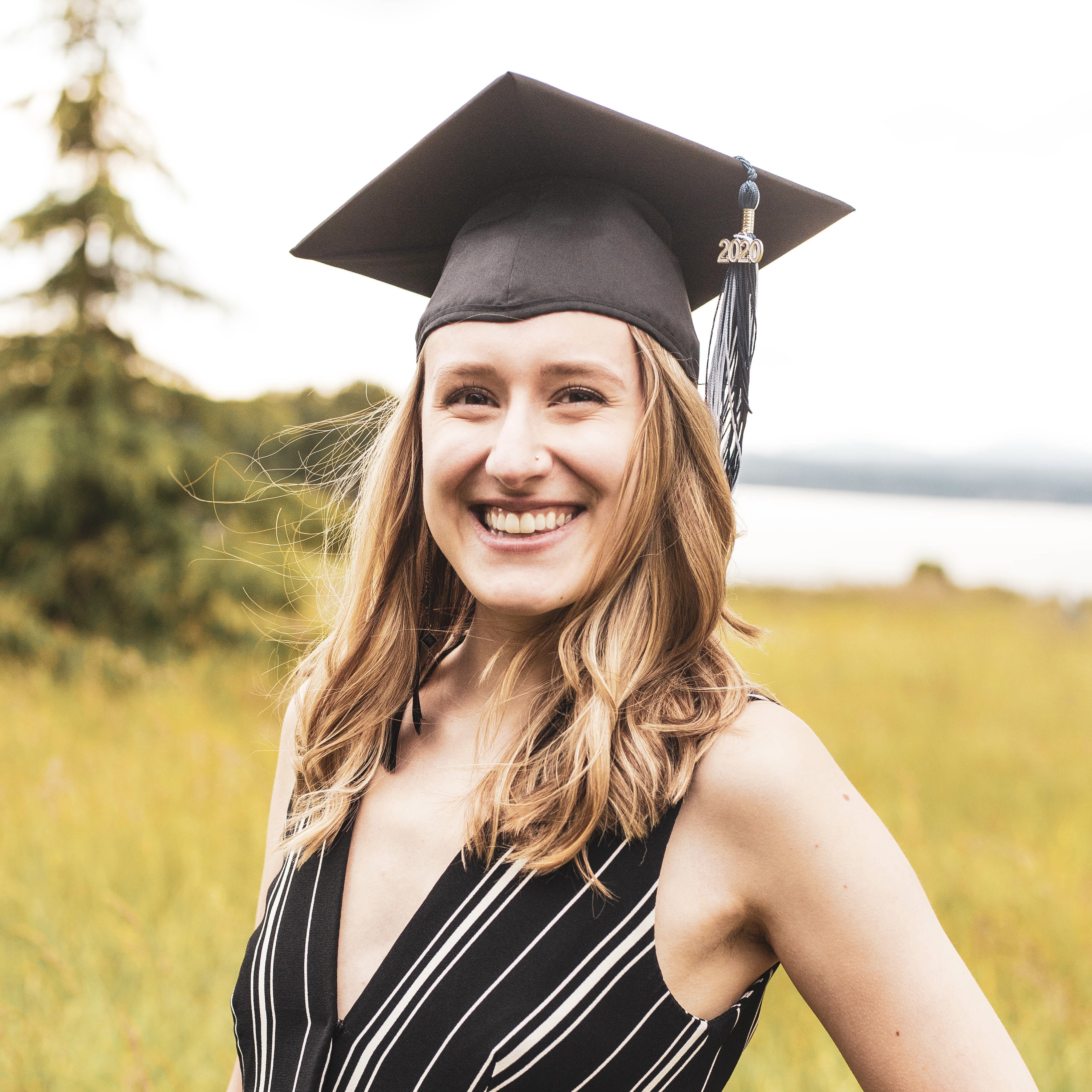 Portait photo of the website owner: a blonde woman smiling while wearing a graduation cap